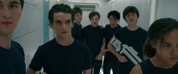 Movie still from “Voyagers” (2021), directed by Neil Burger – A group of young men standing next to each other in a hallway; Medium shot, Low angle