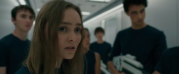 Movie still from “Voyagers” (2021), directed by Neil Burger – A woman standing in front of a group of people; Close Up shot, Over the shoulder angle