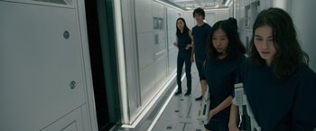 Movie still from “Voyagers” (2021), directed by Neil Burger – A group of people standing next to each other in a room; Medium shot, Low angle