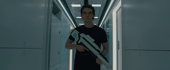 Movie still from “Voyagers” (2021), directed by Neil Burger – A young man holding a gun in a hallway; Medium shot, Low angle