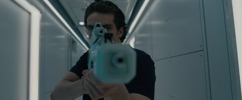 Movie still from “Voyagers” (2021), directed by Neil Burger – A man is holding a gun in a room; Close Up shot, Low angle
