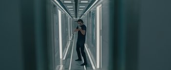 Movie still from “Voyagers” (2021), directed by Neil Burger – A man taking a picture of himself in a hallway; Wide shot, Low angle