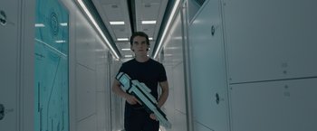Movie still from “Voyagers” (2021), directed by Neil Burger – A young man holding a white object while standing in a hallway; Medium shot, Low angle