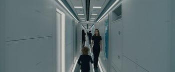 Movie still from “Voyagers” (2021), directed by Neil Burger – A group of people walking down a long hallway; Wide shot, High angle