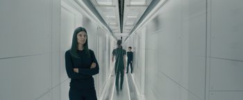Movie still from “Voyagers” (2021), directed by Neil Burger – A woman and two men are walking down a long hallway; Wide shot, Low angle