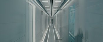 Movie still from “Voyagers” (2021), directed by Neil Burger – A person is walking down a hallway in a building; Wide shot, Overhead angle