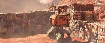 Movie still from “WALL·E” (2008), directed by Andrew Stanton – An orange and yellow robot is standing in front of a pile of garbage; Extreme Wide shot, Low angle