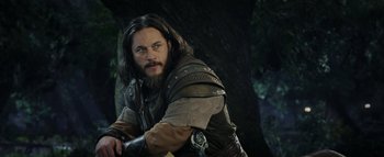 Movie still from “Warcraft” (2016), directed by Duncan Jones – A man with long hair and a beard wearing a leather jacket; Medium shot, Low angle