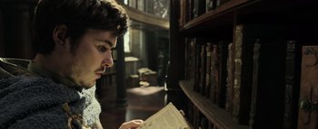 Movie still from “Warcraft” (2016), directed by Duncan Jones – A man is reading a book in a library; Close Up shot, Low angle