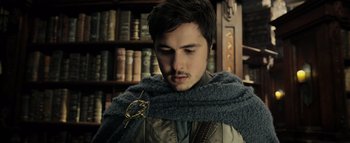 Movie still from “Warcraft” (2016), directed by Duncan Jones – A young man wearing a cape and holding a book; Close Up shot, Low angle