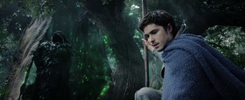 Movie still from “Warcraft” (2016), directed by Duncan Jones – A man sitting in front of a tree in the woods; Medium shot, Low angle