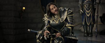 Movie still from “Warcraft” (2016), directed by Duncan Jones – A man dressed as a medieval knight holding a sword; Medium shot, Over the shoulder angle