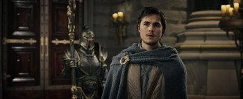 Movie still from “Warcraft” (2016), directed by Duncan Jones – A man wearing a cape standing in front of a statue; Medium shot, Over the shoulder angle