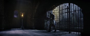 Movie still from “Warcraft” (2016), directed by Duncan Jones – A man standing in front of a jail cell; Wide shot, High angle