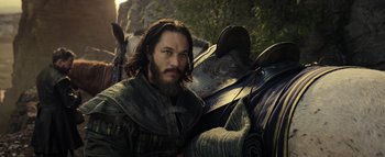 Movie still from “Warcraft” (2016), directed by Duncan Jones – A man with long hair and a beard is sitting on top of a horse; Medium shot, Low angle