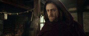 Movie still from “Warcraft” (2016), directed by Duncan Jones – A man with long hair and a beard wearing a red robe; Close Up shot, Low angle