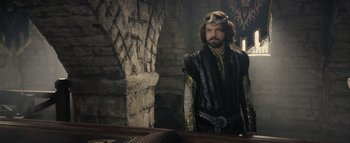Movie still from “Warcraft” (2016), directed by Duncan Jones – A man in a costume standing in front of a brick wall; Medium shot, Over the shoulder angle
