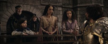 Movie still from “Warcraft” (2016), directed by Duncan Jones – Two young women in medieval garb standing next to each other in front of a stone wall; Medium shot, Over the shoulder angle