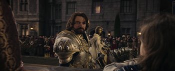 Movie still from “Warcraft” (2016), directed by Duncan Jones – A man dressed as a medieval knight and a woman dressed as an angel in front of a crowd of onlookers; Medium shot, Over the shoulder angle