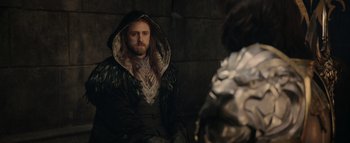 Movie still from “Warcraft” (2016), directed by Duncan Jones – A man with a long beard wearing a hooded jacket; Medium shot, Over the shoulder angle
