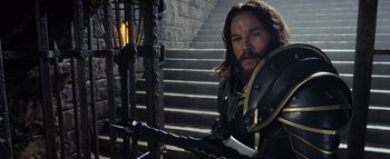 Movie still from “Warcraft” (2016), directed by Duncan Jones – A man with a sword standing in front of a staircase; Medium shot, Over the shoulder angle