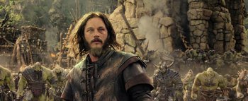 Movie still from “Warcraft” (2016), directed by Duncan Jones – A man with long hair and a beard is wearing a leather jacket; Close Up shot, Low angle