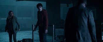 Movie still from “Warm Bodies” (2013), directed by Jonathan Levine – A young man in a red jacket standing next to a metal fence; Medium shot, Over the shoulder angle