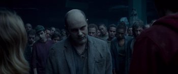 Movie still from “Warm Bodies” (2013), directed by Jonathan Levine – A group of people standing around a man with a bald head; Medium shot, Over the shoulder angle