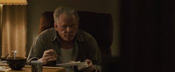 Movie still from “Warrior” (2011), directed by Gavin O'Connor – An older man sitting at a table with a plate in front of him; Medium shot, Over the shoulder angle