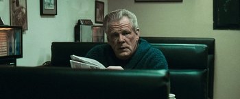 Movie still from “Warrior” (2011), directed by Gavin O'Connor – An older man sitting on a couch reading a newspaper; Close Up shot, Low angle