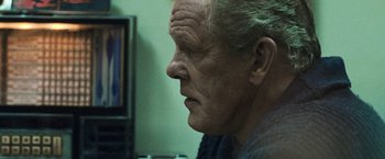 Movie still from “Warrior” (2011), directed by Gavin O'Connor – An older man looking into the distance in front of a television; Close Up shot, Over the shoulder angle