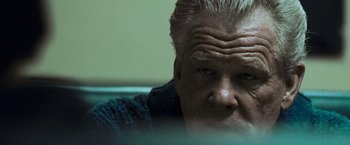 Movie still from “Warrior” (2011), directed by Gavin O'Connor – An older man with gray hair and blue eyes looking at the camera; Close Up shot, Low angle