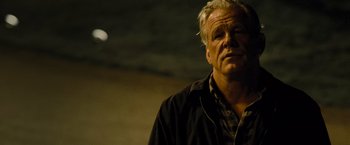 Movie still from “Warrior” (2011), directed by Gavin O'Connor – An older man wearing a black shirt and a black jacket; Close Up shot, Low angle