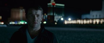 Movie still from “Warrior” (2011), directed by Gavin O'Connor – A man standing in front of a city at night; Close Up shot, Over the shoulder angle