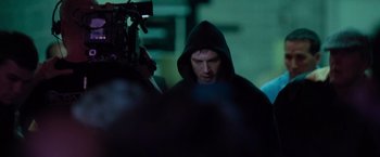 Movie still from “Warrior” (2011), directed by Gavin O'Connor – A man wearing a black hooded sweatshirt is being filmed by a camera; Medium shot, Over the shoulder angle