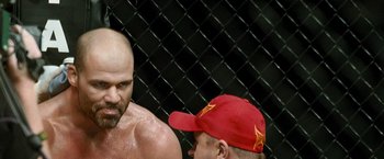 Movie still from “Warrior” (2011), directed by Gavin O'Connor – A man in a red hat is standing next to another man in a red hat; Close Up shot, Over the shoulder angle