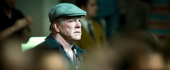 Movie still from “Warrior” (2011), directed by Gavin O'Connor – An older man wearing a green hat and a black jacket; Close Up shot, Over the shoulder angle