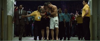 Movie still from “Warrior” (2011), directed by Gavin O'Connor – A couple of men standing next to each other on top of a field; Wide shot, Over the shoulder angle