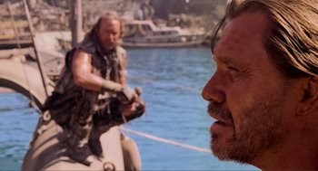 Movie still from “Waterworld” (1995), directed by Kevin Reynolds – A man on a boat in the water with another man in the background; Close Up shot, Over the shoulder angle