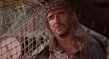 Movie still from “Waterworld” (1995), directed by Kevin Reynolds – A person with a beard wearing a hat; Close Up shot, Low angle