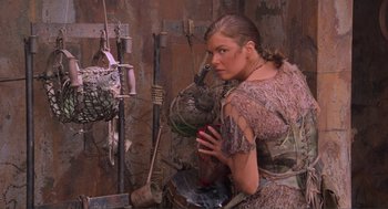 Movie still from “Waterworld” (1995), directed by Kevin Reynolds – A woman is standing in front of a bunch of junk; Medium shot, Low angle