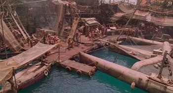 Movie still from “Waterworld” (1995), directed by Kevin Reynolds – An aerial view of an area with boats and people in the water; Extreme Wide shot, High angle