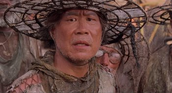Movie still from “Waterworld” (1995), directed by Kevin Reynolds – A man wearing a straw hat with barbed wire on it; Close Up shot, Low angle