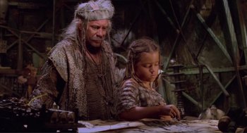 Movie still from “Waterworld” (1995), directed by Kevin Reynolds – A man and a young girl sitting at a table; Medium shot, High angle