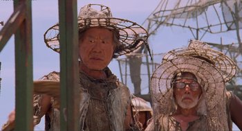 Movie still from “Waterworld” (1995), directed by Kevin Reynolds – A man and a woman wearing straw hats and standing next to each other; Close Up shot, Low angle