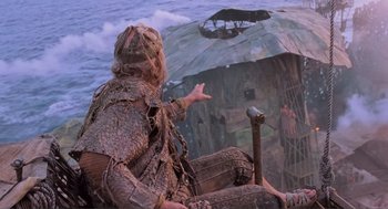 Movie still from “Waterworld” (1995), directed by Kevin Reynolds – A man sitting on the ground with a cane; Wide shot, Low angle