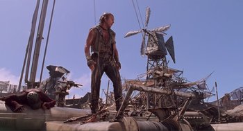 Movie still from “Waterworld” (1995), directed by Kevin Reynolds – A man standing on top of a boat in the water; Wide shot, Low angle