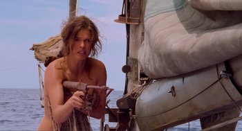 Movie still from “Waterworld” (1995), directed by Kevin Reynolds – A beautiful young woman standing on top of a boat in the water; Medium shot, Low angle