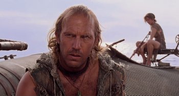 Movie still from “Waterworld” (1995), directed by Kevin Reynolds – A person with long blond hair; Close Up shot, Over the shoulder angle