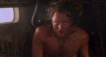 Movie still from “Waterworld” (1995), directed by Kevin Reynolds – A shirtless man with long curly hair and a necklace; Close Up shot, Overhead angle